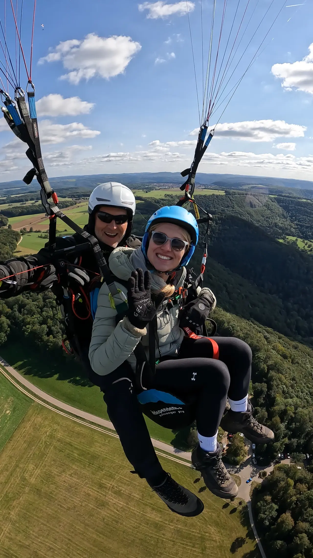 Passagierin winkt glücklich beim Tandemflug über der Alb