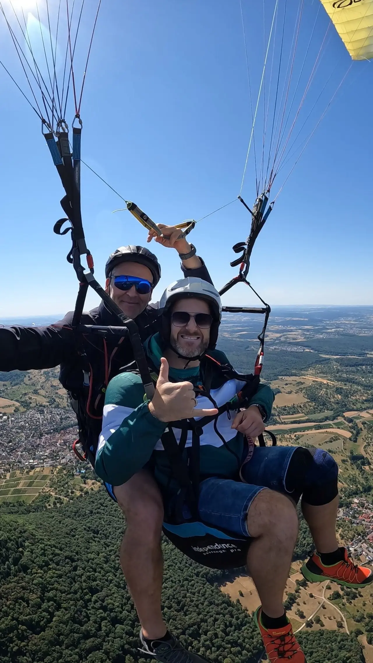 Passagier zeigt den Shaka-Gruß beim Tandemflug über der Schwäbischen Alb